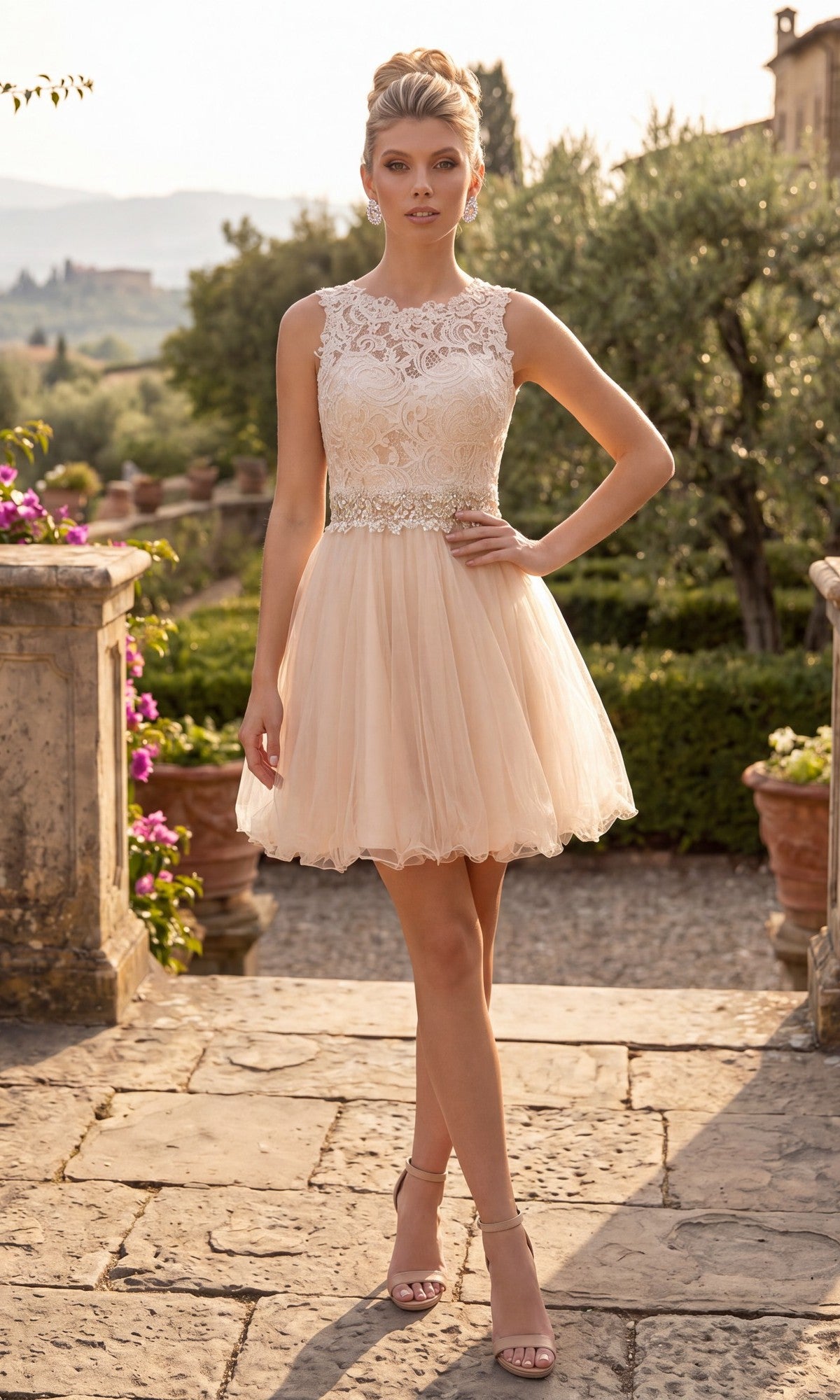 A woman stands outdoors on a stone path lined with greenery and potted plants, wearing the Short Homecoming Dress: Chicas C9350 in champagne. The sleeveless, knee-length dress features an illusion lace bodice and an elegant A-line tulle skirt.